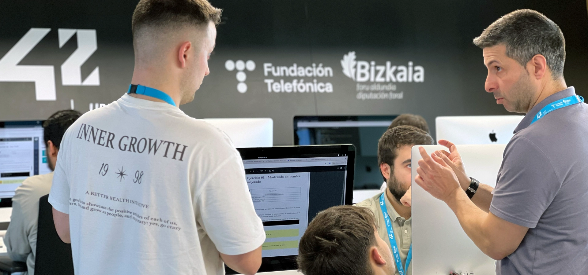 portada-dsl-ia-machine-learning-nov-26 Group of people collaborating at computer desks in a tech workspace, with Fundación Telefónica and Bizkaia logos on the wall behind them.
